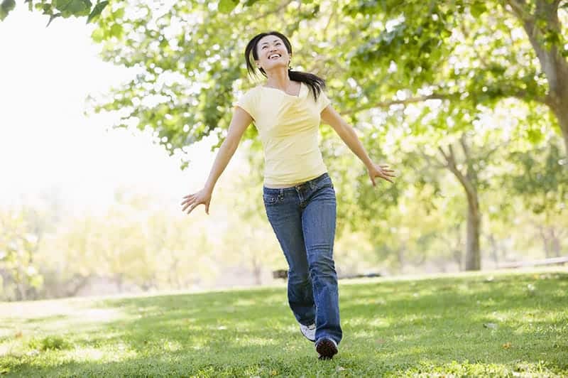 How-to-Live-a-Life-Free-of-Bad-Habits1 woman in yellow shirt running happily in a park illustrating how to live a life free of bad habits