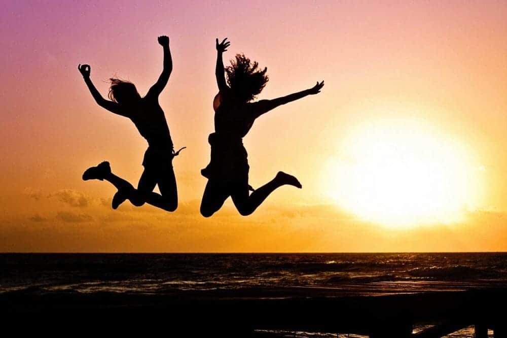 two people jumping in silhouette on beach at sunset illustrating self motivation in the face of recovery from addiction