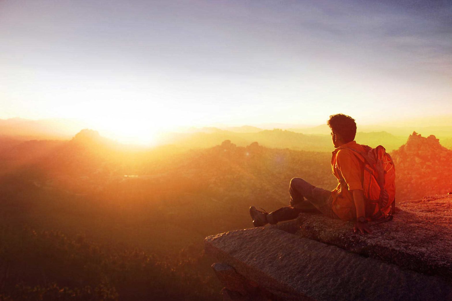 hiker overlooking sunrise from cliff illustrating the choice misery in addiction or freedom in life