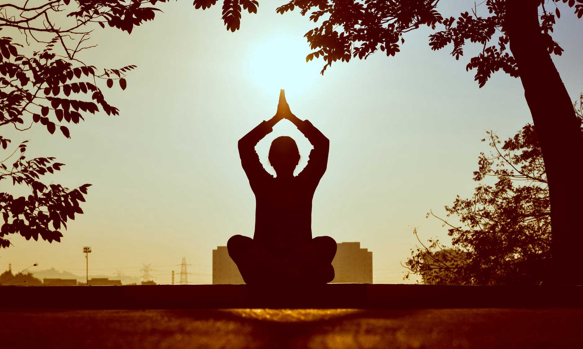 person in yoga pose silhouetted by the sun demonstrating yoga as an addiction recovery tool