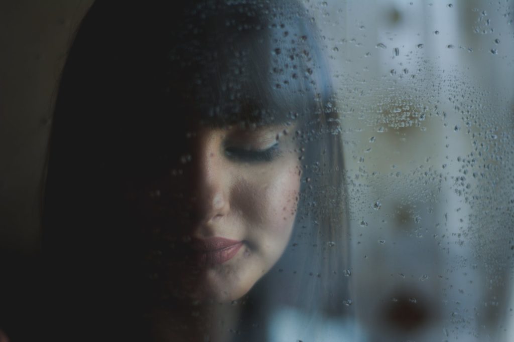 hopeful woman looking down behind rainy window as mom finds hope for drug addicted daughter
