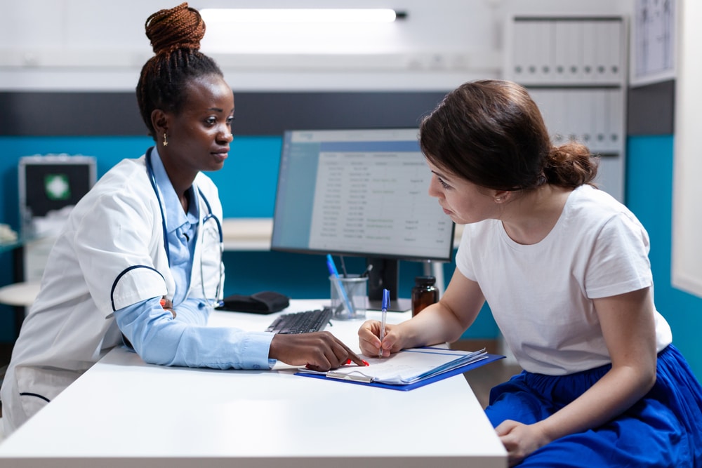 doctor explaining to new patient how long alcohol rehab is and signing papers